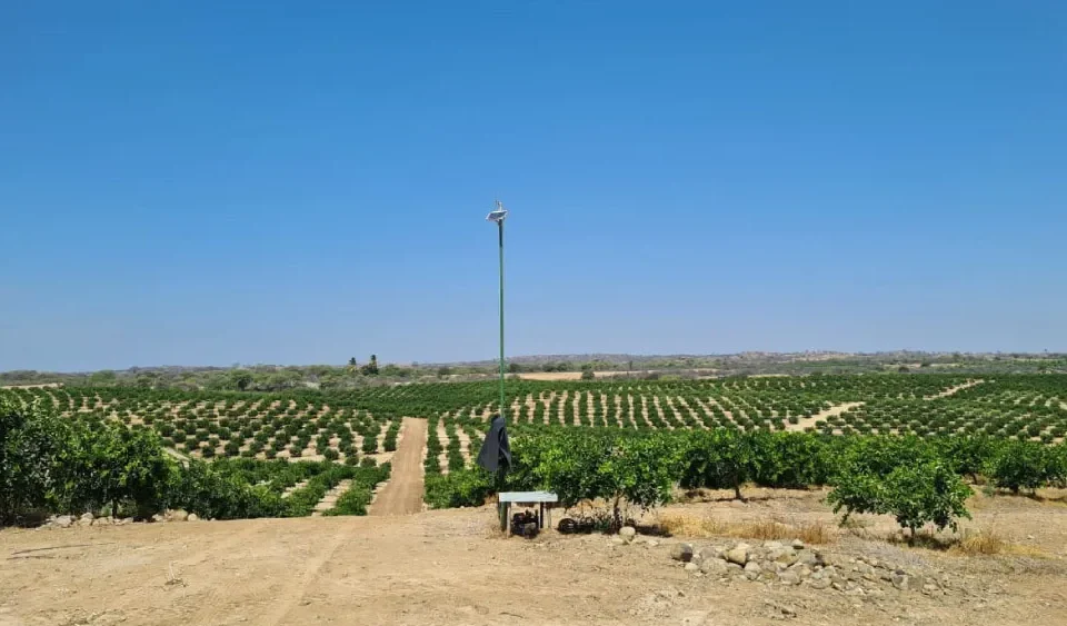 Farmland with connected sprinkler network and a hardware device mounted on a post for advanced Sprinkler System control.