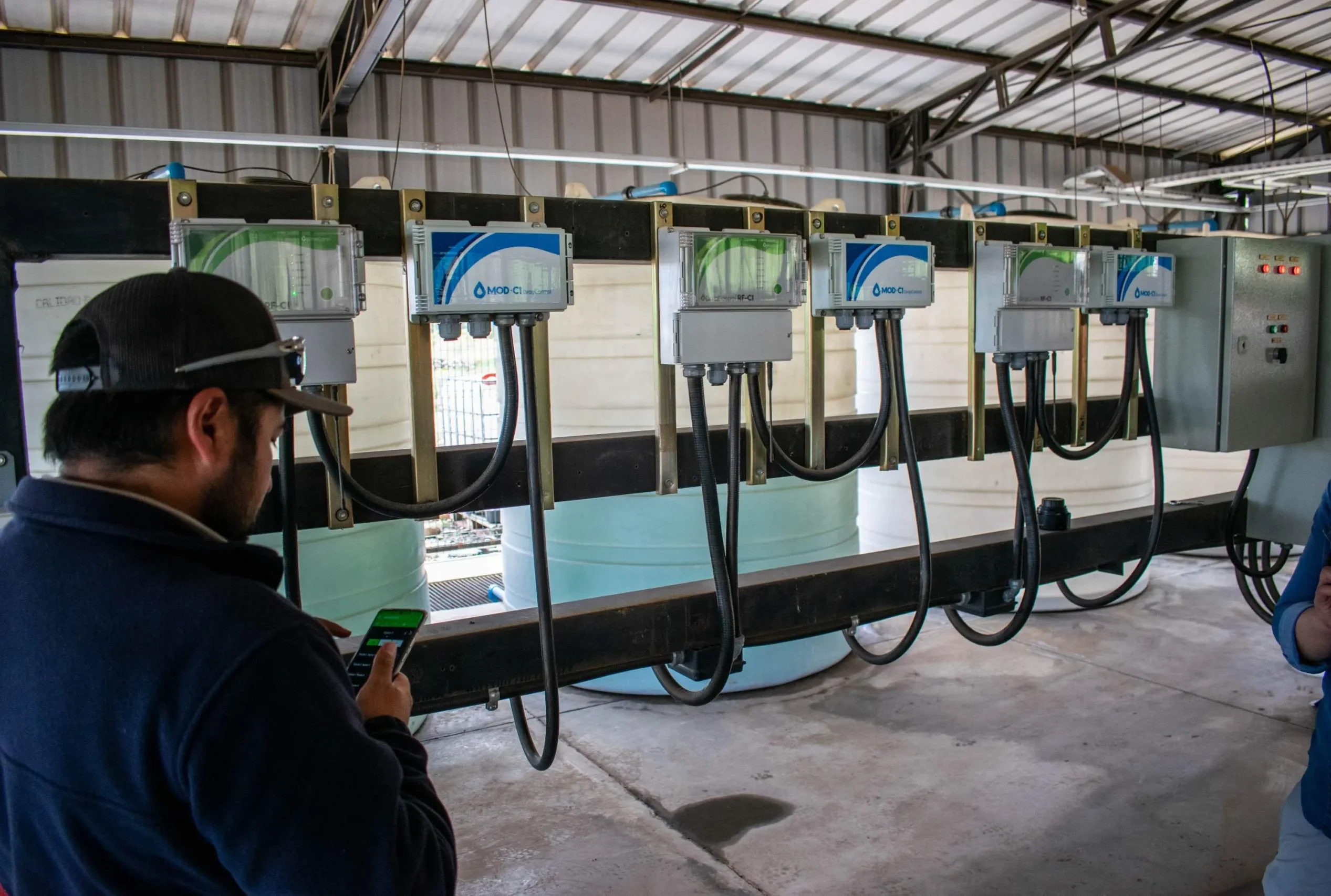 Technician checking DROP CONTROL hardware in an agricultural shed, ensuring functionality with irrigation control software