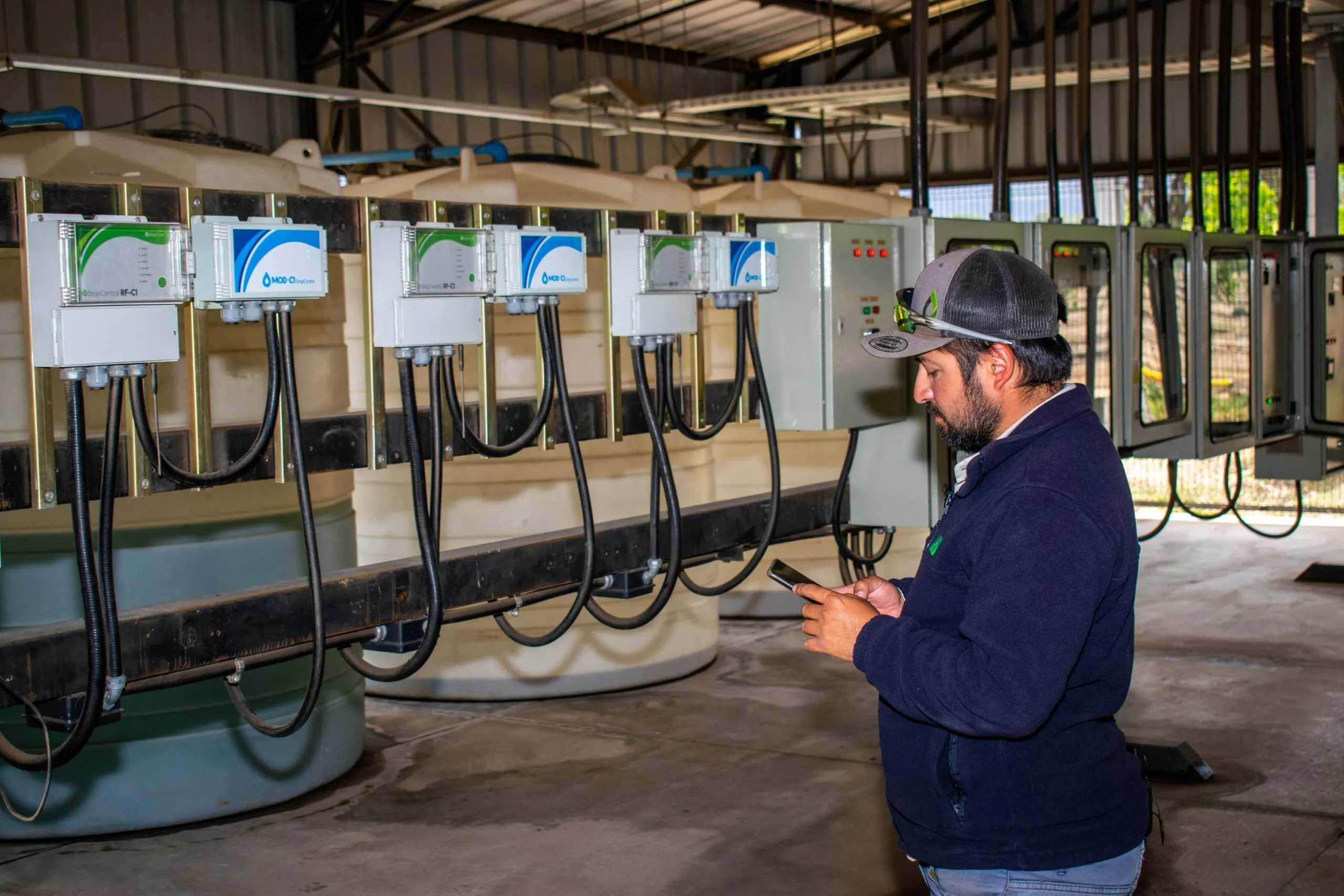 Farmer checking real-time data on his phone connected to DROP CONTROL units, improving efficiency with agtech solutions